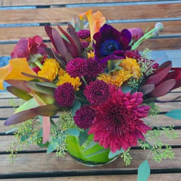 Colorful mixed bouquet in a glass vase on a wooden table