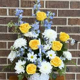Yellow roses and white daisies in a white basket with blue flowers