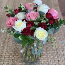 Bouquet of pink, white, and red roses in a glass vase