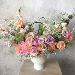 Pastel bouquet of roses, dahlias, and snapdragons in a white vase