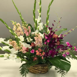 Mixed floral arrangement in a woven basket with white, pink, and purple blooms