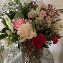 Mixed bouquet of pink, white, and red flowers in a glass vase