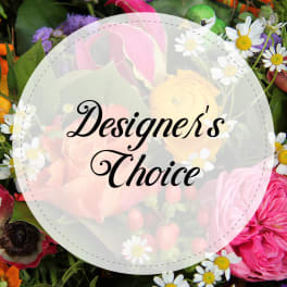 Mixed bouquet with roses, calla lilies, and daisies behind a "Designer’s Choice" label
