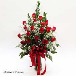 Red roses arranged in a clear glass vase with a red ribbon