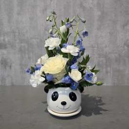 White and blue flowers arranged in a panda-face ceramic pot