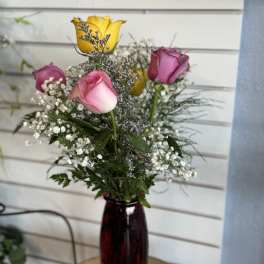 Mixed roses in a red glass vase with baby's breath
