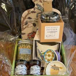 Gift basket with tea, honey, mugs, and a decorative bottle-shaped container