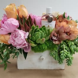 Flower arrangement in a white drawer box with a bottle of sweet almond oil