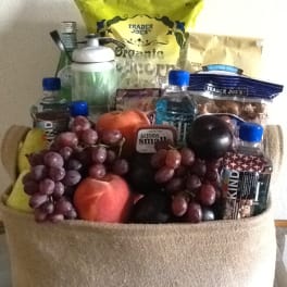Gift basket filled with fruit, snacks, and bottled drinks