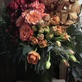 Bouquet of roses, tulips, and orchids in a tall green vase