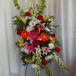 Tall standing floral spray with red roses, pink lilies, and white daisies