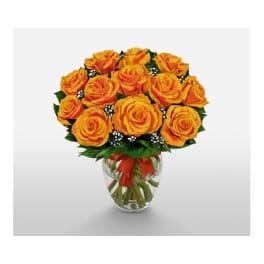 Orange roses in a clear glass vase with a red ribbon