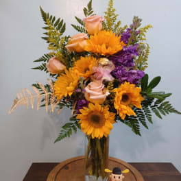 Sunflower and peach rose arrangement in a glass vase