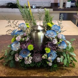 Floral urn arrangement with blue roses and purple chrysanthemums around a metal vase