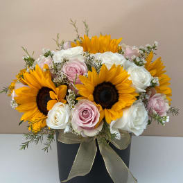 Bouquet of sunflowers and pink and white roses in a black box
