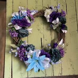 Heart-shaped floral wreath with purple and blue flowers and ribbon