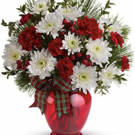 Red and white floral arrangement in a red vase with plaid ribbon