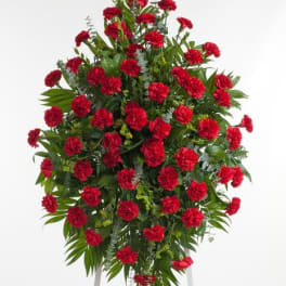 Standing spray of red carnations with greenery on an easel