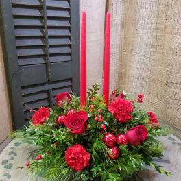 Red roses and carnations with tall red candles in a low centerpiece