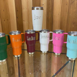 Six personalized insulated tumblers in assorted colors on a glass table