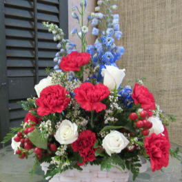 Basket arrangement of red carnations, white roses, and blue delphinium