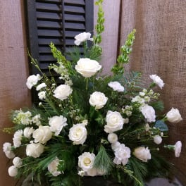 White roses and carnations arranged in a large vase with greenery