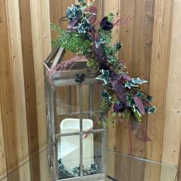Decorative lantern with faux greenery and dark purple flowers