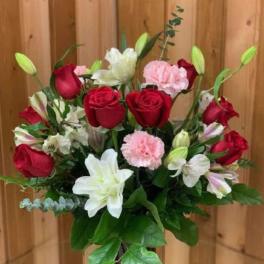 Bouquet of red roses, white lilies, and pink carnations in a red vase