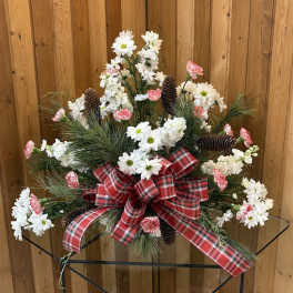Christmas floral arrangement with white daisies, pink carnations, pinecones, and a red plaid bow