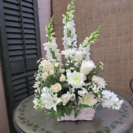 White floral arrangement in a pale basket on a glass table