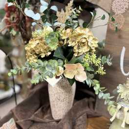 Arrangement of pale hydrangeas and greenery in a tall vase