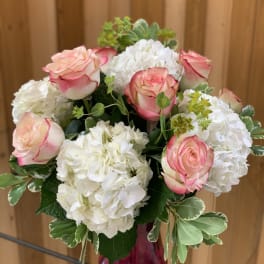 Pink-edged roses and white hydrangeas in a glass vase