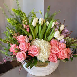 Pink roses and white tulips arranged in a white bowl vase