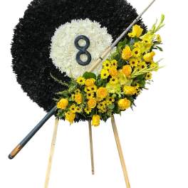Black and white floral funeral wreath on an easel with yellow flowers