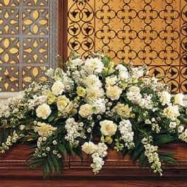 Large white floral arrangement on a wooden casket