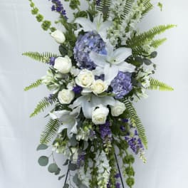 Tall standing floral spray with white lilies, roses, and purple blooms