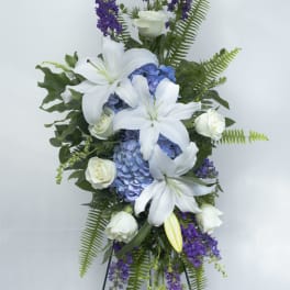 Tall floral spray with white lilies, blue hydrangeas, and purple flowers