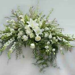 White lilies and roses in a long floral spray with greenery