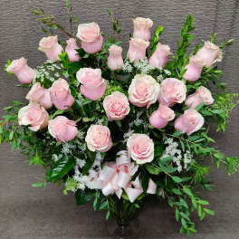 Pink roses arranged in a clear glass vase with a ribbon bow