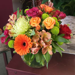 Mixed bouquet of roses, gerbera daisies, and chrysanthemums in a glass vase