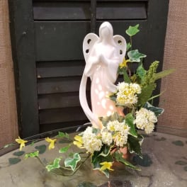 Ceramic angel figurine with white and yellow flowers and ivy