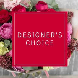 Mixed bouquet of red and pink flowers with a red square label reading Designer's Choice