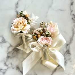 Two small pastel floral bouquets with cream ribbons on a marble surface