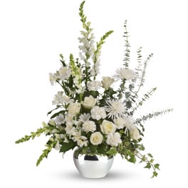 Tall white flower arrangement with roses, mums, carnations, and snapdragons in a round silver vase