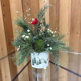 Pine arrangement in a white pot with a red bird ornament