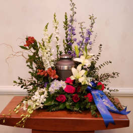Funeral urn surrounded by mixed flowers in white, purple, pink, and red