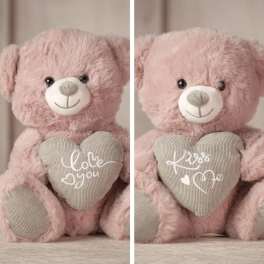 Pink teddy bear holding a heart pillow with embroidered text