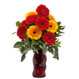 Tall arrangement of red and yellow gerbera daisies in a red glass vase