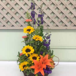 Basket arrangement with sunflowers, orange lilies, and purple flowers