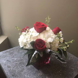 Red roses and white hydrangeas in a red glass vase